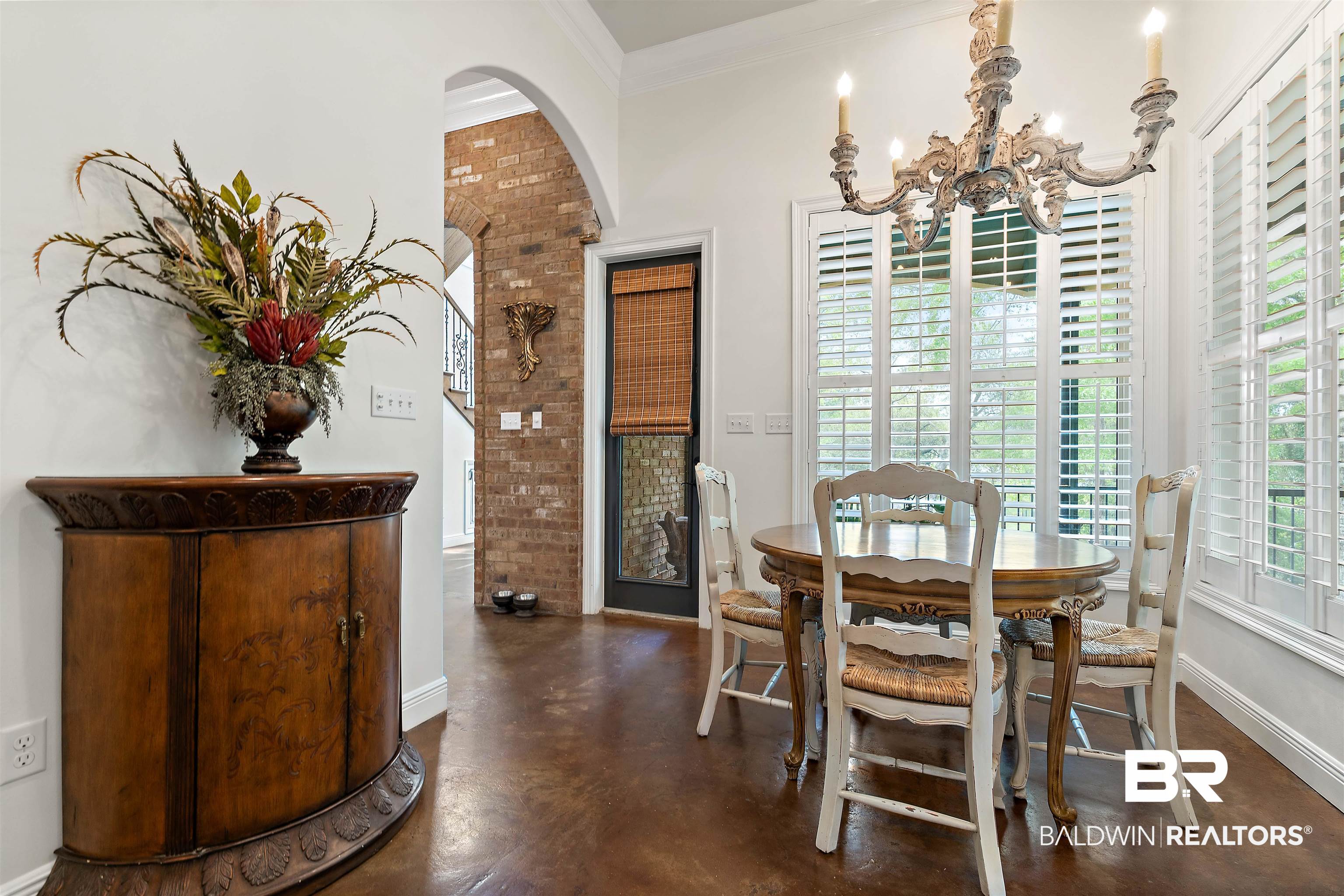 3584 Rue Royal Mobile, AL 36693 - Photo 12 of 35 Dining area featuring finished concrete flooring, baseboards, arched walkways, ornamental molding, and a notable chandelier