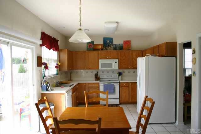 311 Grassy Point Road Apex, NC 27502 - Photo 2 of 10 Easily maneuver around this kitchen with warm oak cabinets, tile backsplash & plenty of cabinet & counter space! Breakfast nook leads to patio/backyard! Tile flooring!