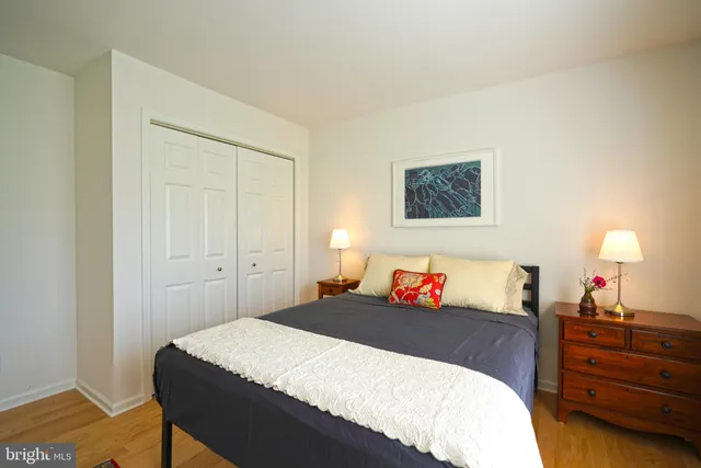 a bedroom with a bed and a lamp on dresser
