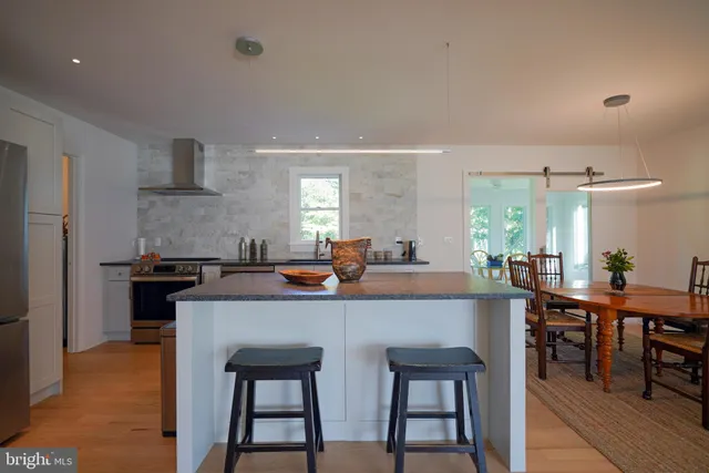 a kitchen with stainless steel appliances a table chairs and a refrigerator