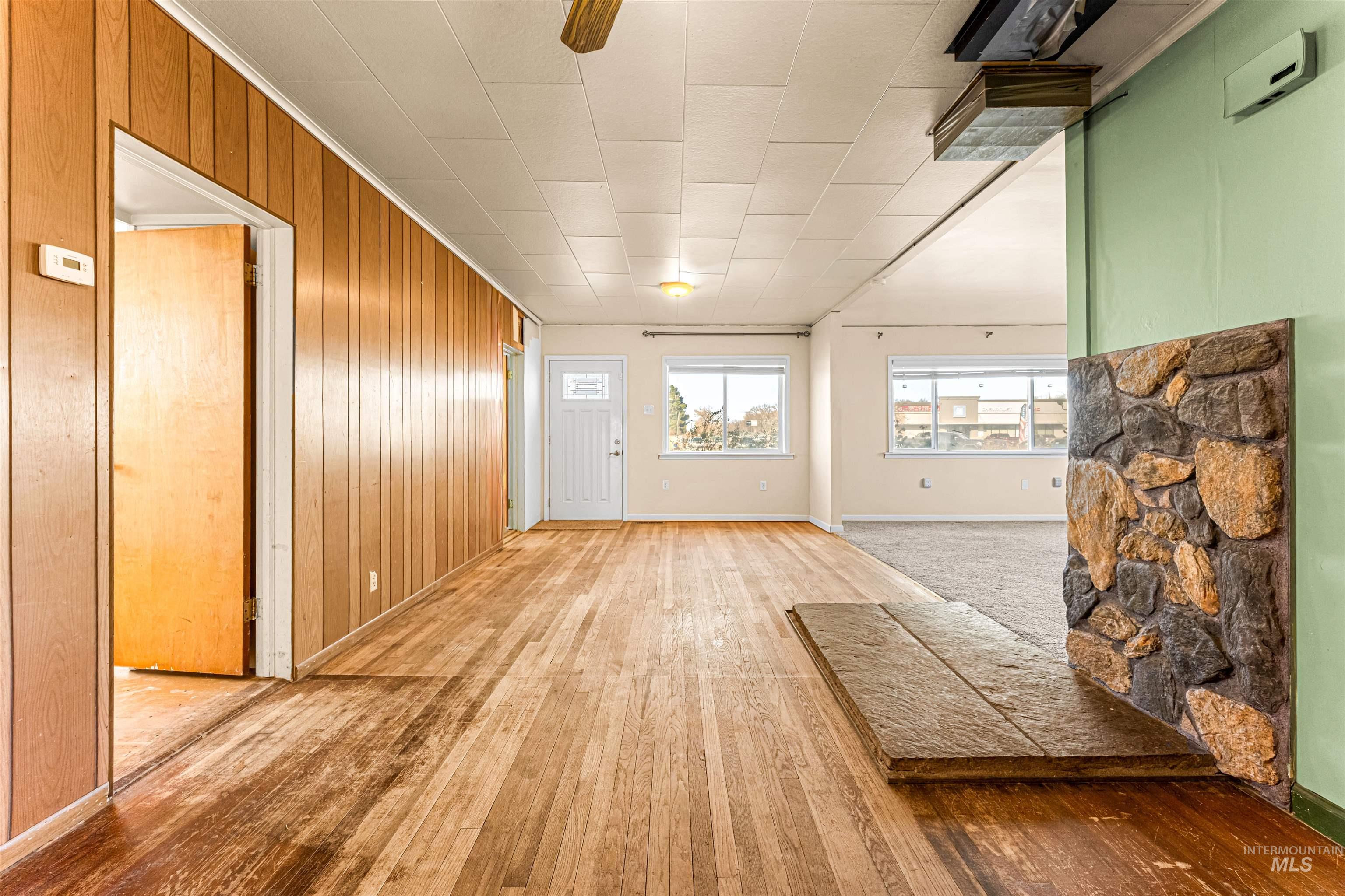 1115 Airbase Road Mountain Home, ID 83647 - Photo 20 of 32 Unfurnished living room with wooden walls, light wood-style floors, and ornamental molding