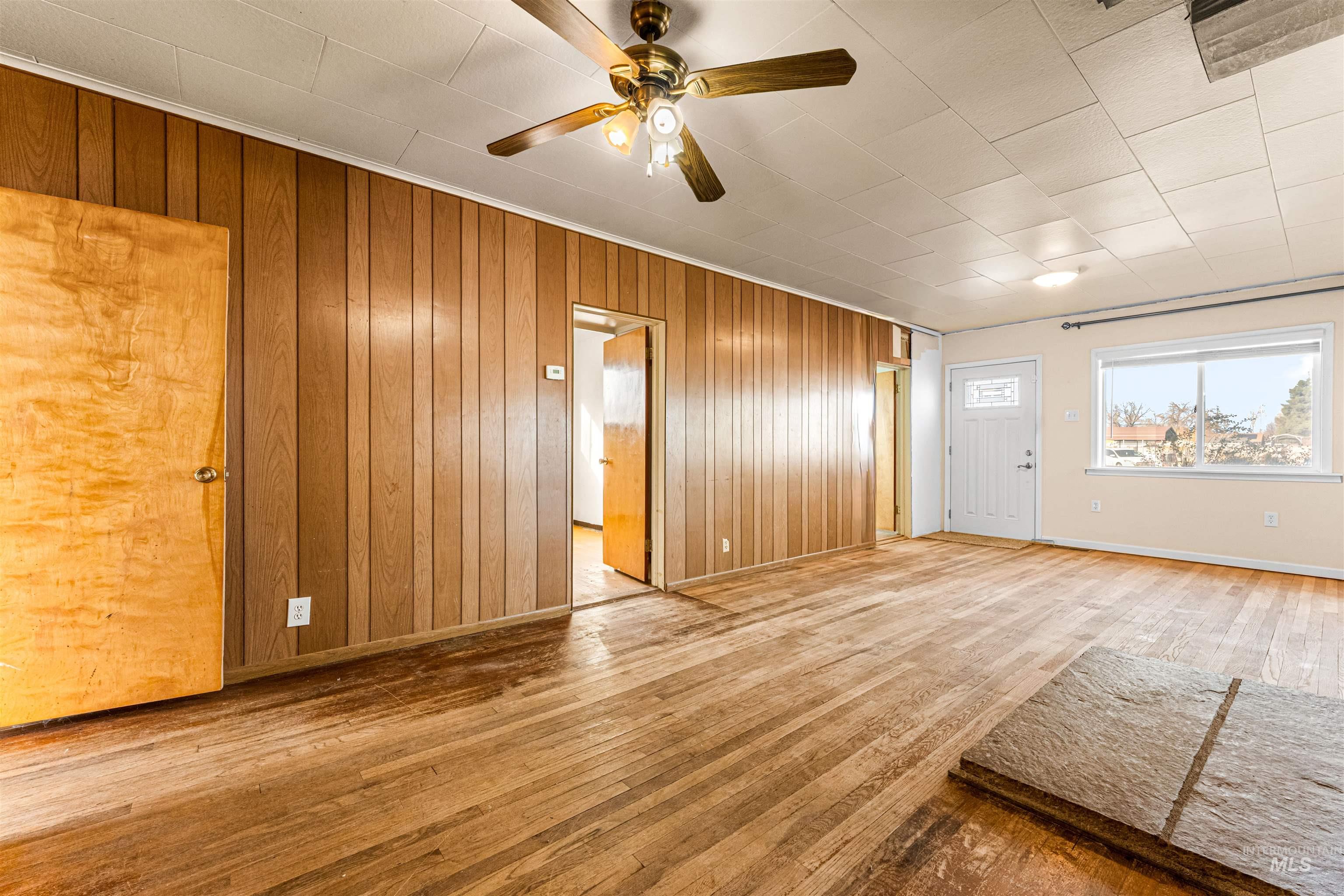 1115 Airbase Road Mountain Home, ID 83647 - Photo 21 of 32 Unfurnished living room featuring hardwood / wood-style flooring, wooden walls, and a ceiling fan