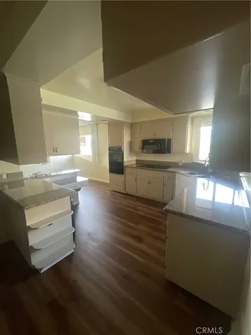 a kitchen with stainless steel appliances wooden floors and view living room