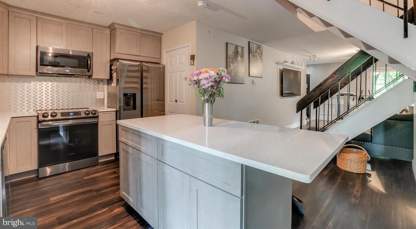 2132 Cartwright Place Reston, VA 20191 - Photo 8 of 21 a kitchen with stainless steel appliances kitchen island wooden floors granite counter tops and white cabinets