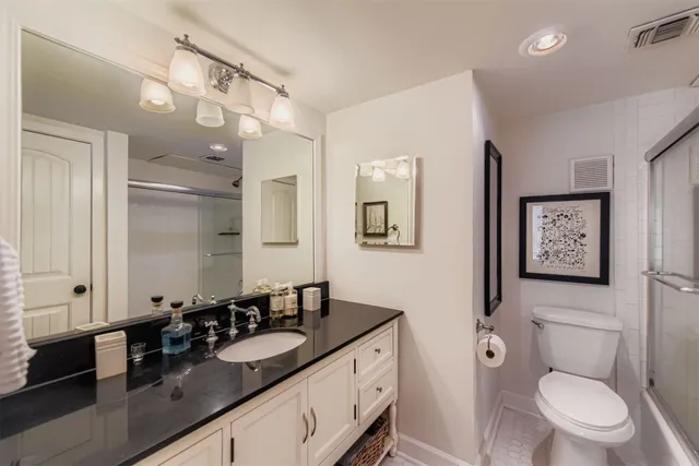 a bathroom with a granite countertop toilet sink and mirror