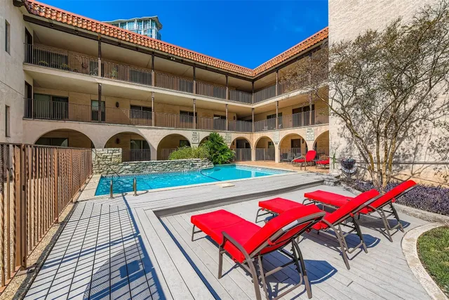 a view of swimming pool with red chairs in front of a house