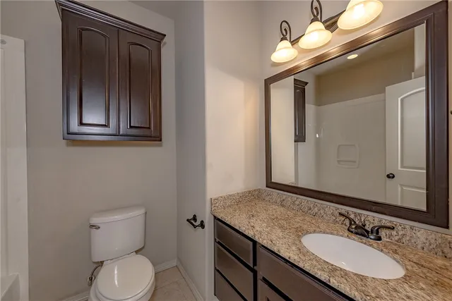 a bathroom with a granite countertop toilet a sink and a mirror