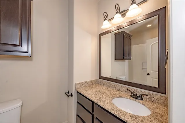 a bathroom with a granite countertop sink a mirror and a toilet