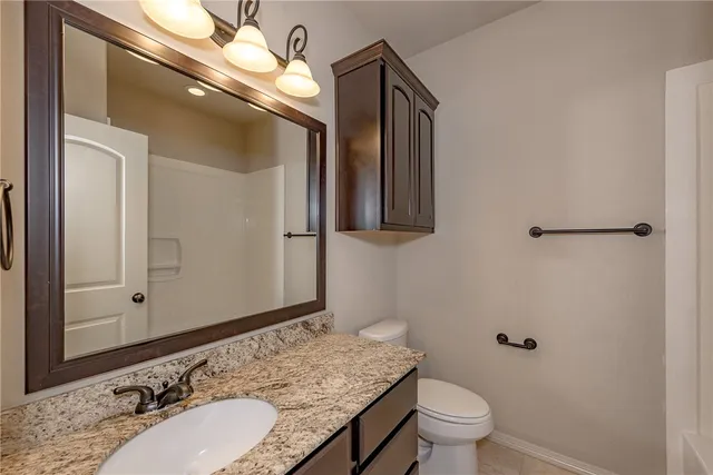 a bathroom with a granite countertop sink toilet a mirror and vanity