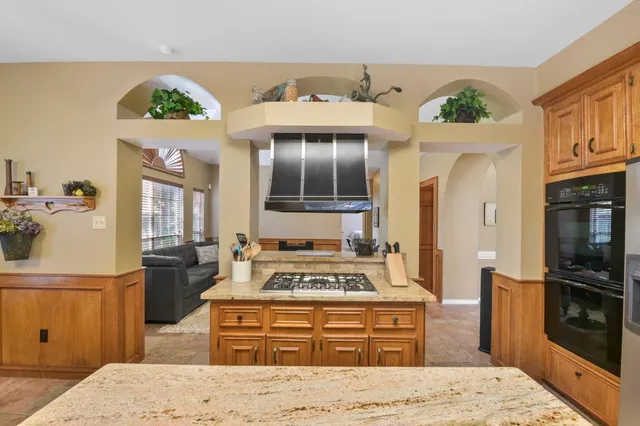 a living room with stainless steel appliances kitchen island granite countertop a stove and a refrigerator
