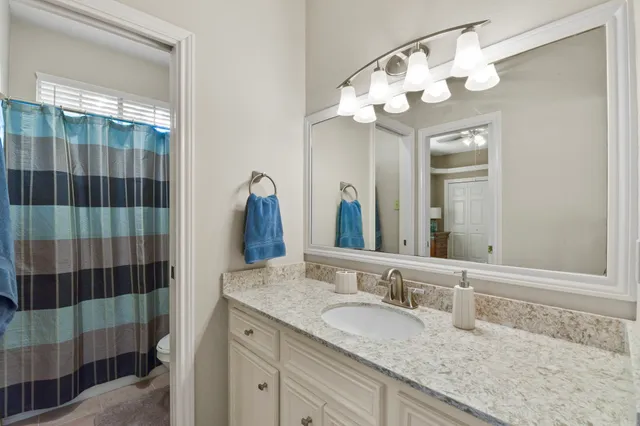a bathroom with a granite countertop sink a mirror and shower