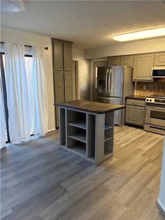 a kitchen with kitchen island granite countertop a sink cabinets and stainless steel appliances
