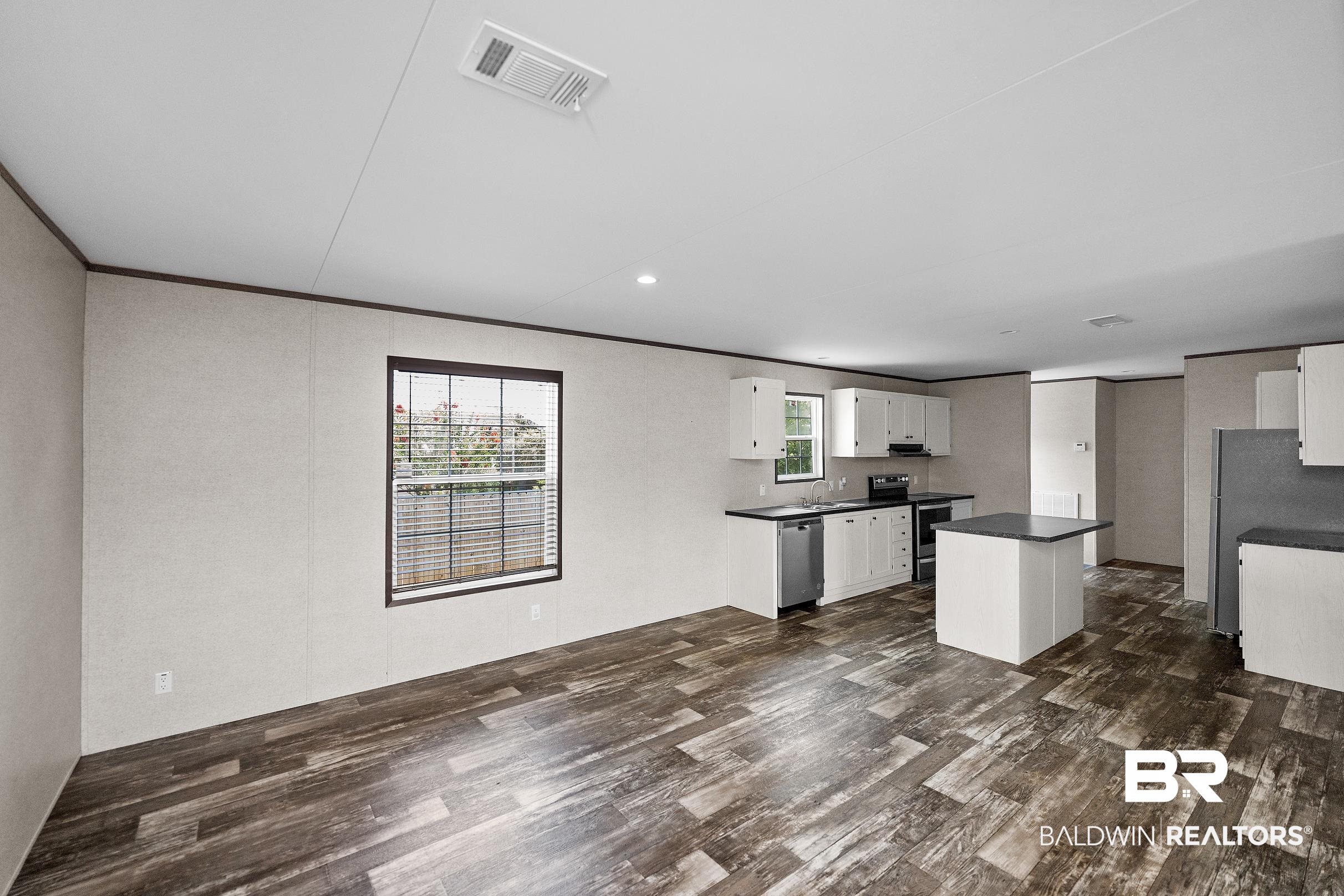 21601 Westside Loop Silverhill, AL 36576 - Photo 12 of 42 Open-concept living area featuring wood-finish flooring, white cabinetry, dark countertops, a kitchen island, and stainless steel appliances
