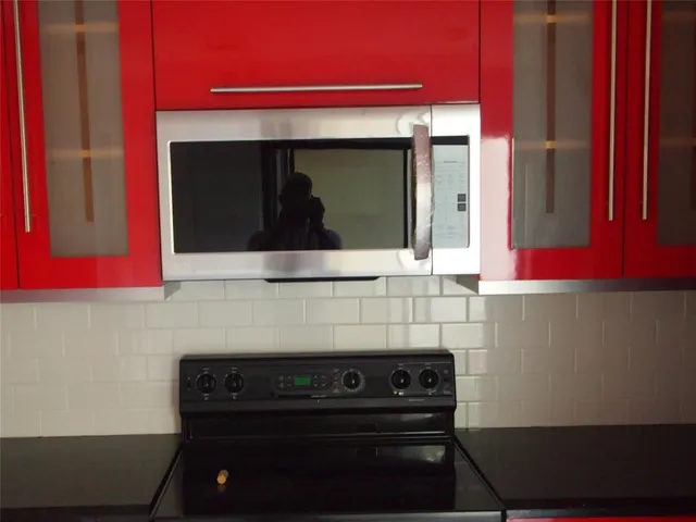 a kitchen with stainless steel appliances granite countertop a red stove and cabinets