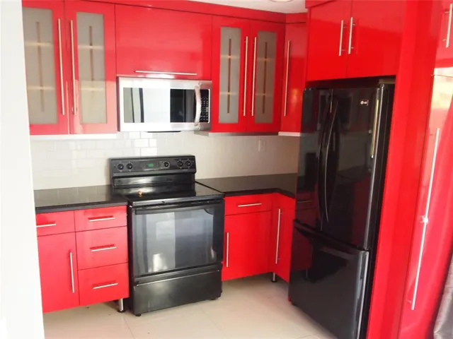 a kitchen with red cabinets a sink and a stove