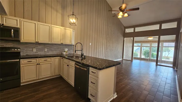 a kitchen with stainless steel appliances granite countertop a stove a sink and a microwave