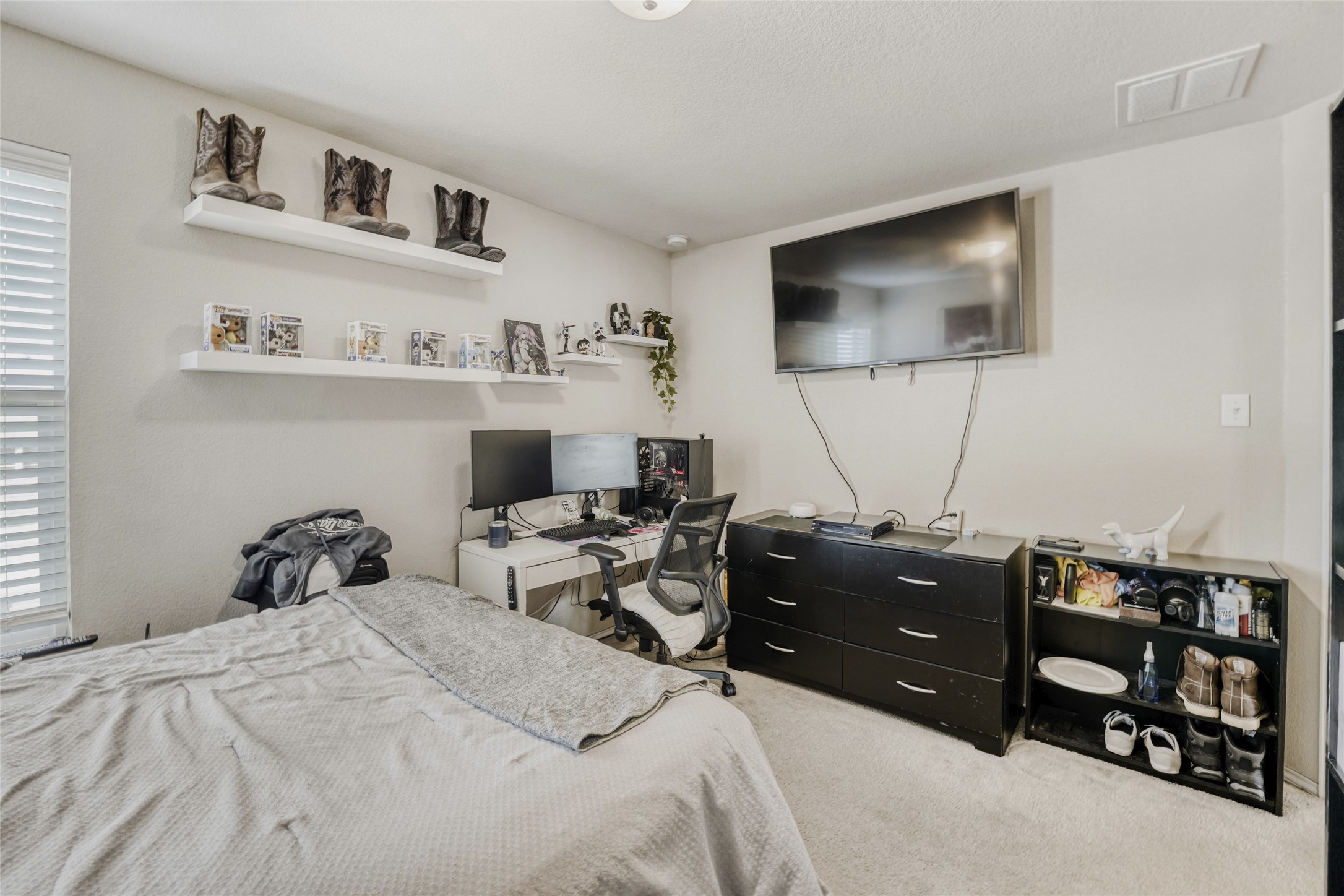 13604 Vigilance Street Manor, TX 78653 - Photo 21 of 28 a bedroom with a bed and a flat tv screen on the dresser