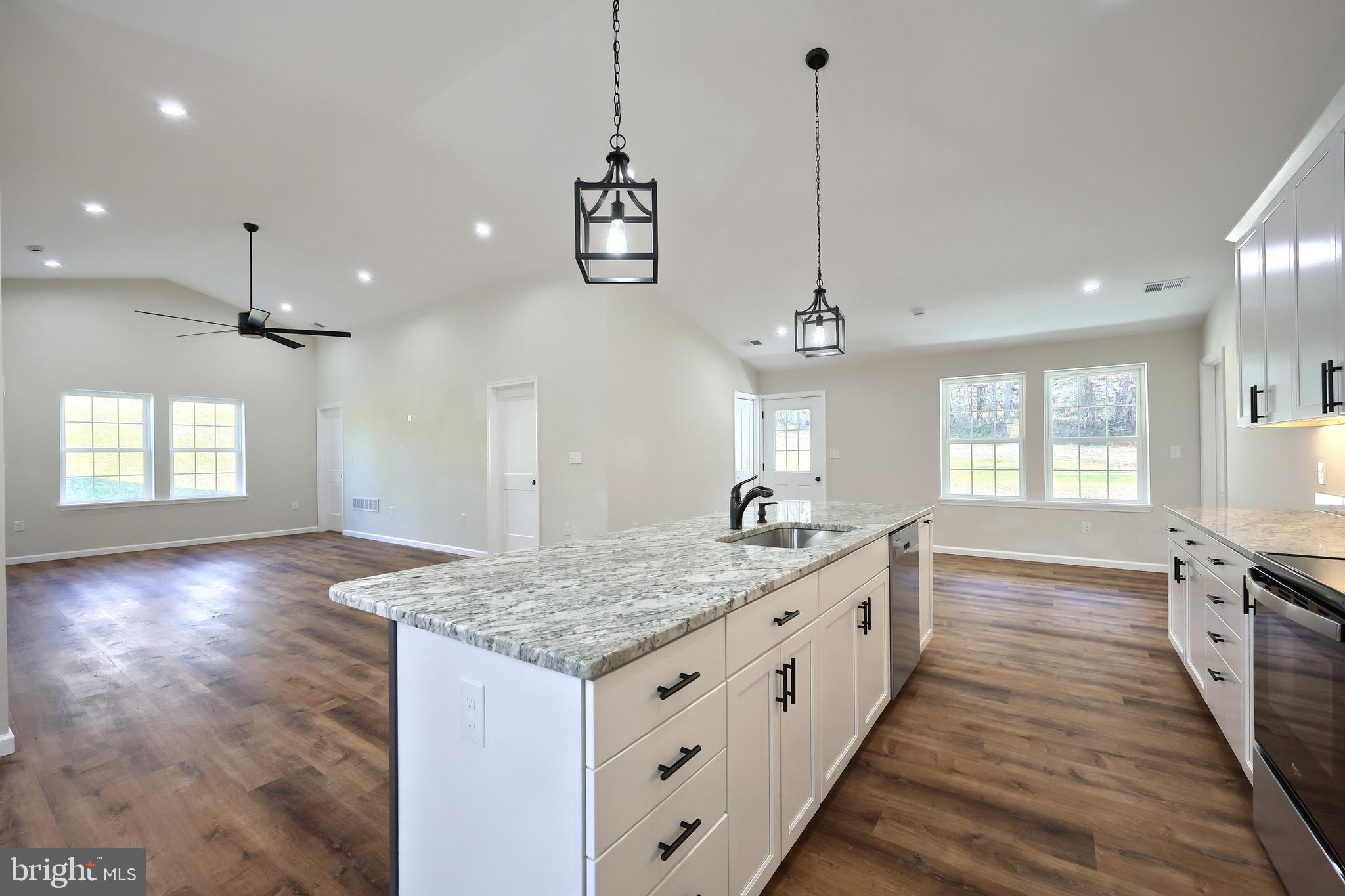 10640 Enfield Road Felton, PA 17322 - Photo 35 of 59 a large kitchen with kitchen island a stove a sink dishwasher a dining table and chairs with wooden floor