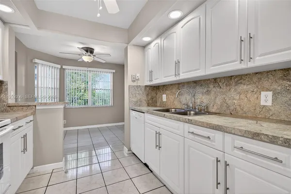a kitchen with granite countertop white cabinets and window