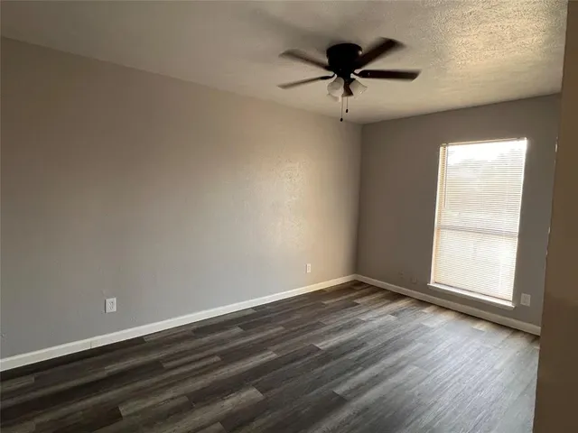 an empty room with wooden floor and ceiling fan