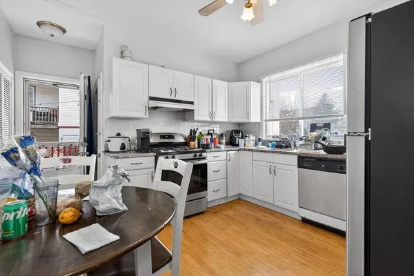 a kitchen with stainless steel appliances granite countertop a sink dishwasher stove refrigerator dining table and chairs