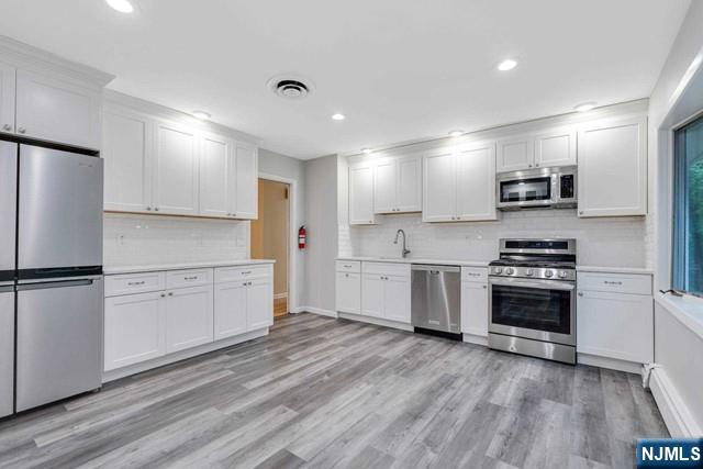 32 Rock Road Englewood Cliffs, NJ 07632 - Photo 6 of 30 a kitchen with granite countertop white cabinets and stainless steel appliances