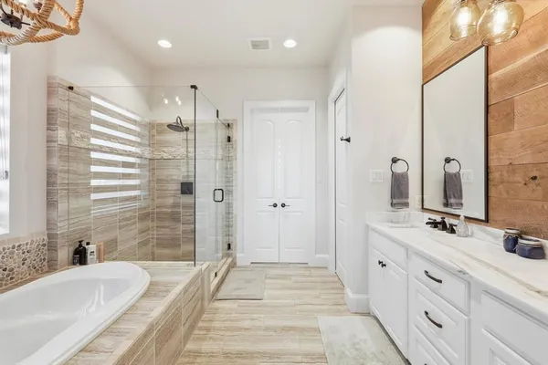 a bathroom with a double vanity sink a mirror a bathtub and shower