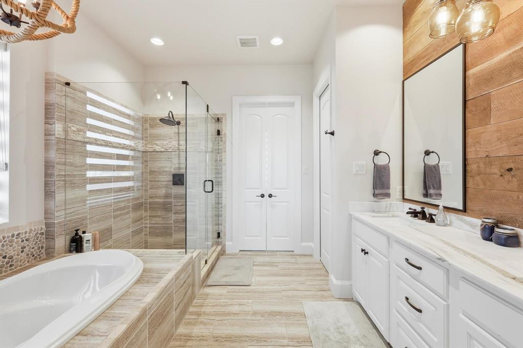 7105 West Hells Gate Drive Strawn, TX 76475 - Photo 13 of 39 a bathroom with a double vanity sink a mirror a bathtub and shower