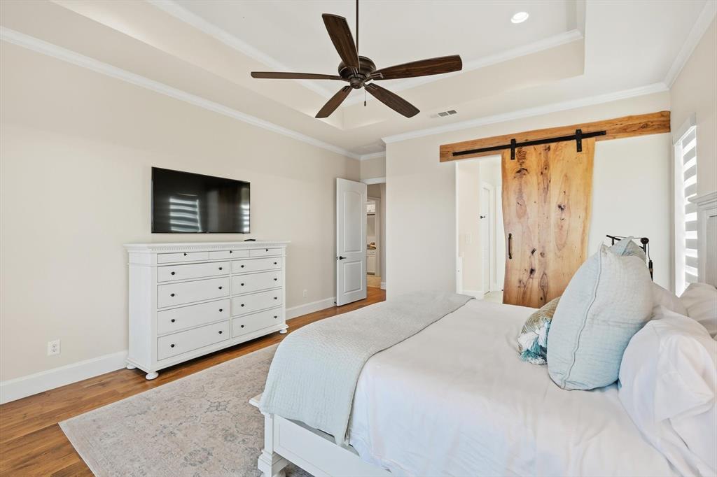 7105 West Hells Gate Drive Strawn, TX 76475 - Photo 17 of 39 a bedroom with a bed a dresser and a chandelier