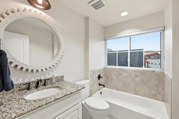 a bathroom with a granite countertop sink mirror vanity and bathtub