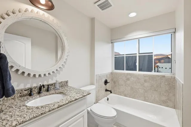 a bathroom with a granite countertop sink mirror vanity and bathtub