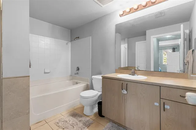 a bathroom with a granite countertop sink toilet mirror and bathtub