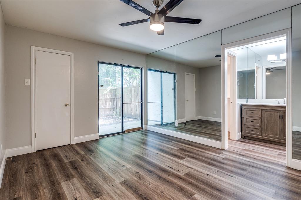 5840 Spring Valley Road, Unit 803 Dallas, TX 75254 - Photo 6 of 12 Inviting primary suite offers 2 walk-in closets, ceiling fan, sliding glass door that opens to the backyard and en-suite bathroom.