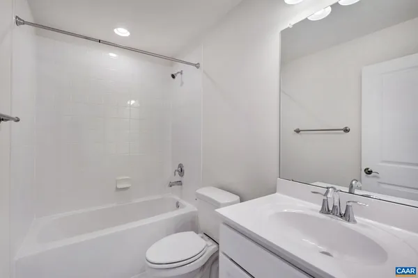 a bathroom with a bathtub shower sink vanity mirror and toilet