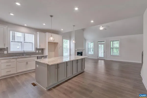 a large kitchen with stainless steel appliances granite countertop a large center island attached withe living room