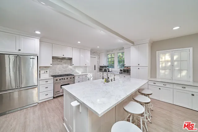 a kitchen with stainless steel appliances granite countertop a sink a stove a refrigerator cabinets and living room view