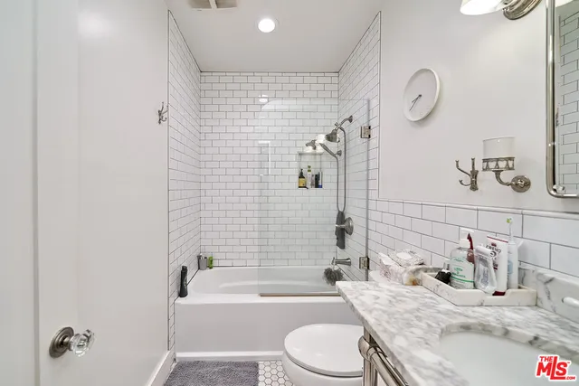 a bathroom with a granite countertop sink mirror toilet and bathtub