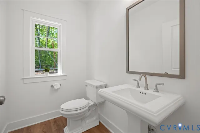 an empty room with wooden floor windows and fan