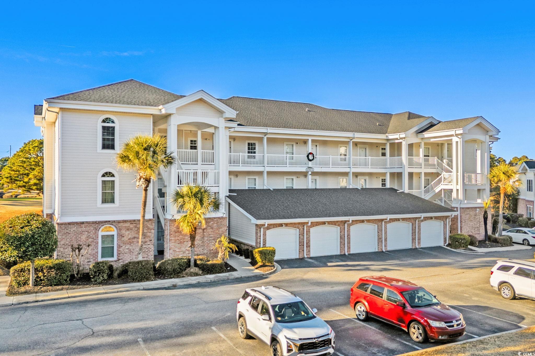 View of property with uncovered parking and stairway
