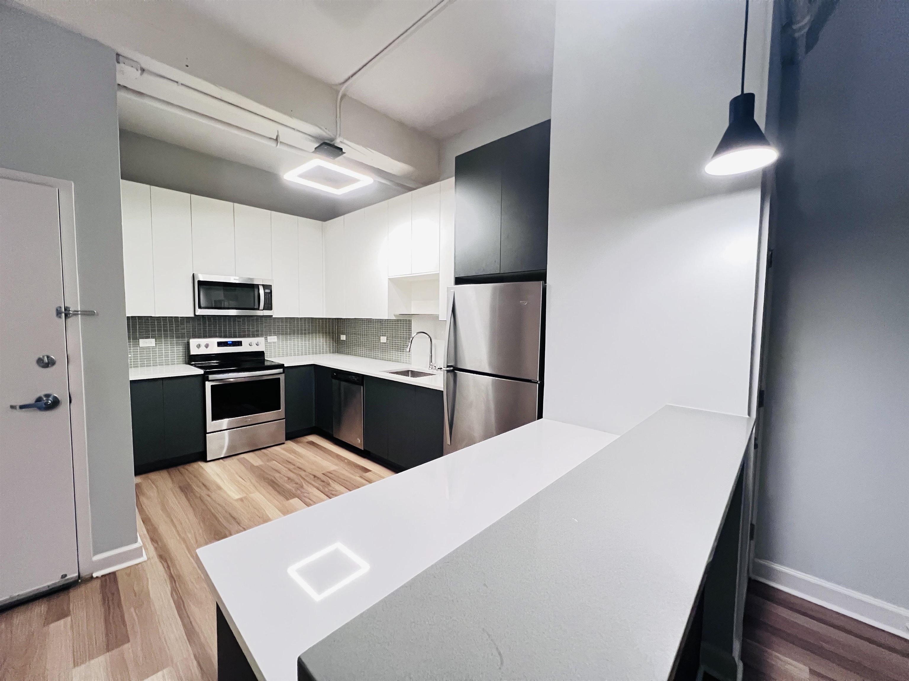 160 Lafayette Street, Unit 52207 Jersey City, NJ 07304 - Photo 12 of 25 a kitchen with kitchen island a counter top space cabinets stainless steel appliances and a ceiling fan