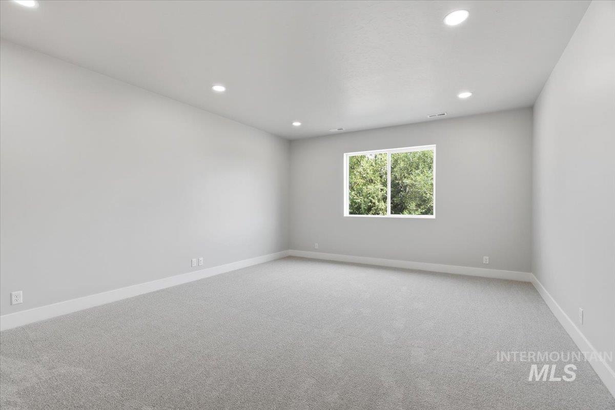 4317 Tropic Way Caldwell, ID 83607 - Photo 31 of 47 Bright, light-filled bedroom showcasing recessed ceiling lighting, neutral wall finishes, neutral carpet flooring, and a large dual-pane window framing natural landscaping views