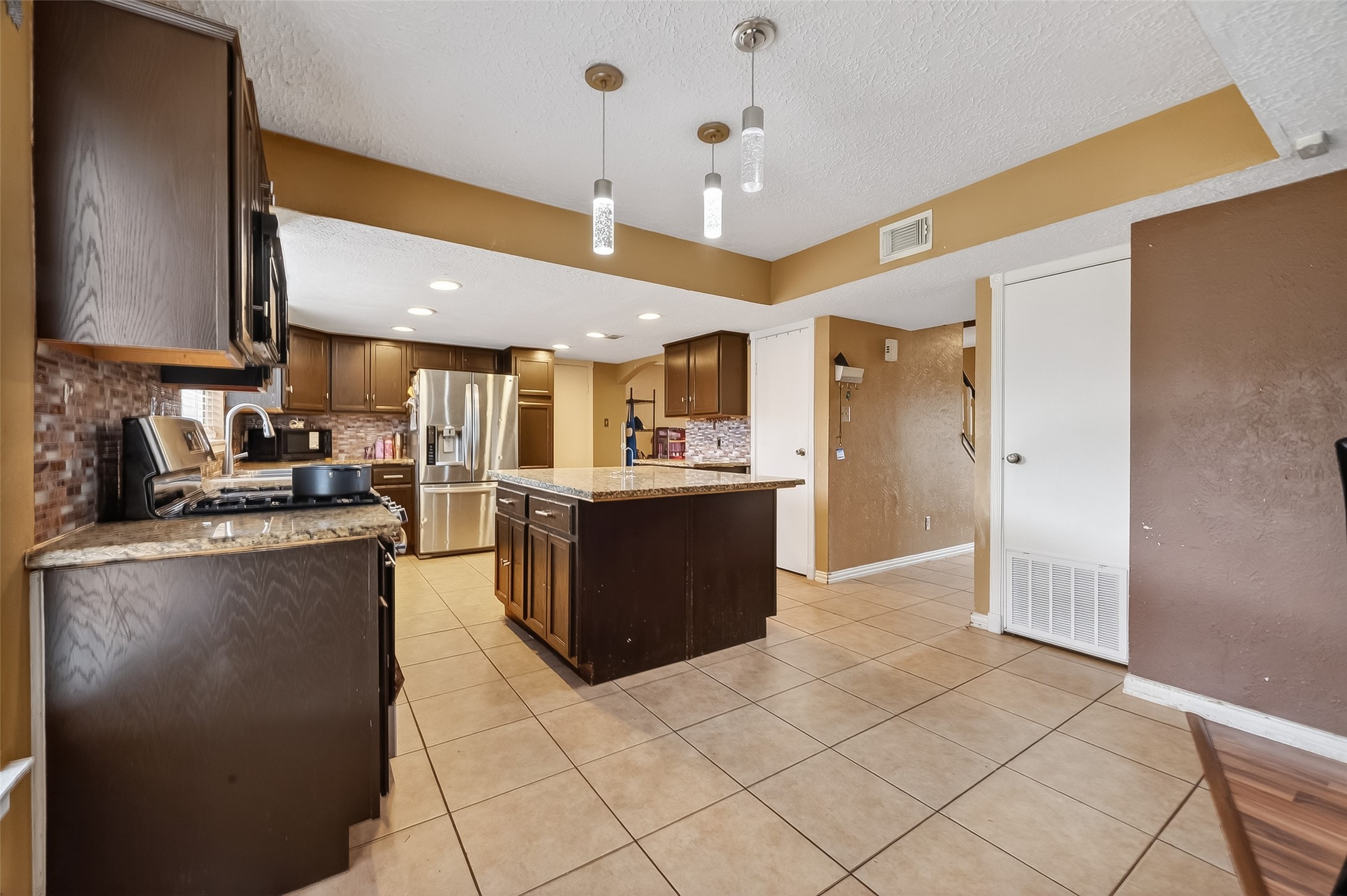 16006 El Toro Court Webster, TX 77598 - Photo 7 of 19 a kitchen with stainless steel appliances kitchen island granite countertop a refrigerator and a sink