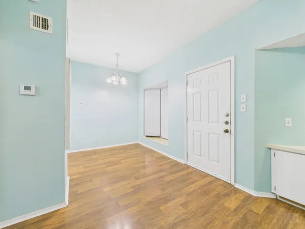 a view of an empty room with wooden floor and closet
