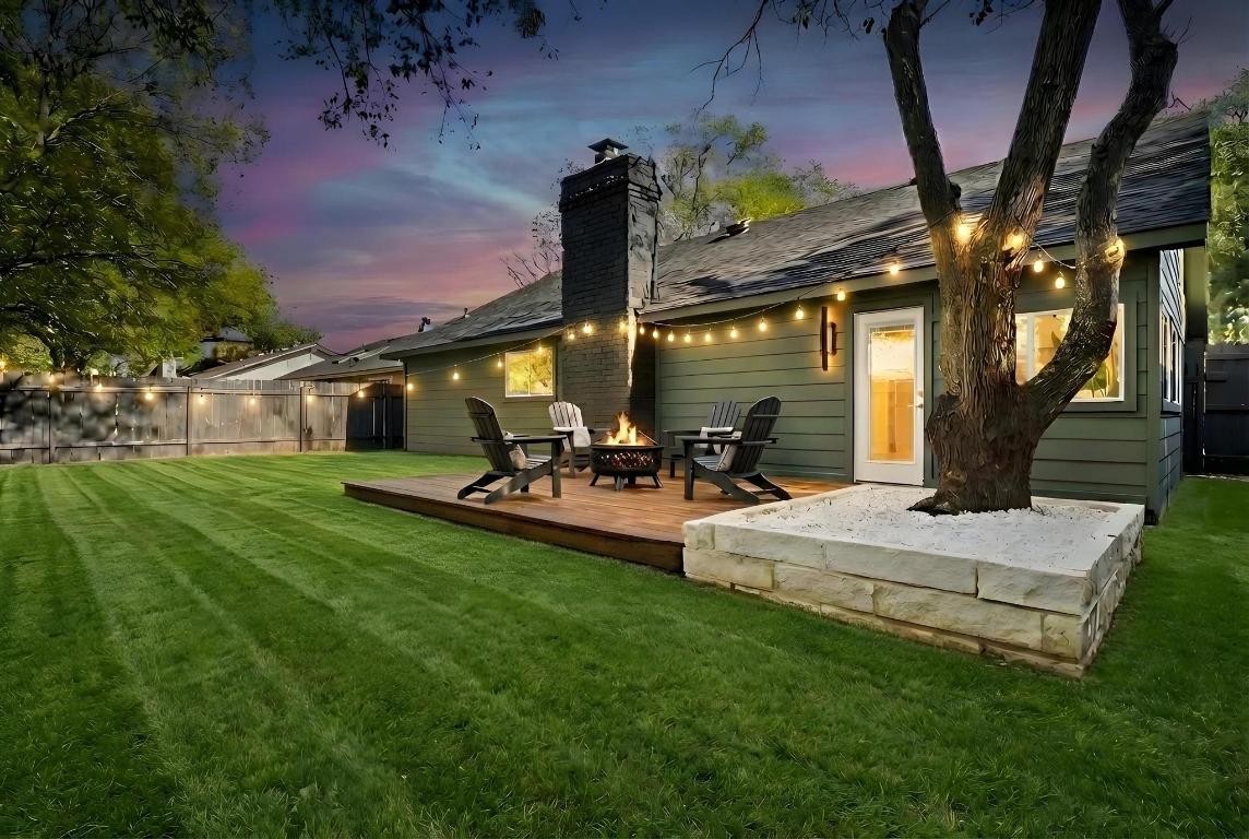 7010 Meadow Run Austin, TX 78745 - Photo 20 of 26 Back of house at dusk featuring an outdoor fire pit, a chimney, and a deck