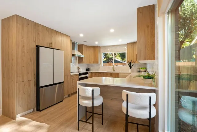 a kitchen with stainless steel appliances granite countertop a refrigerator a stove a sink and a dining table with garden view