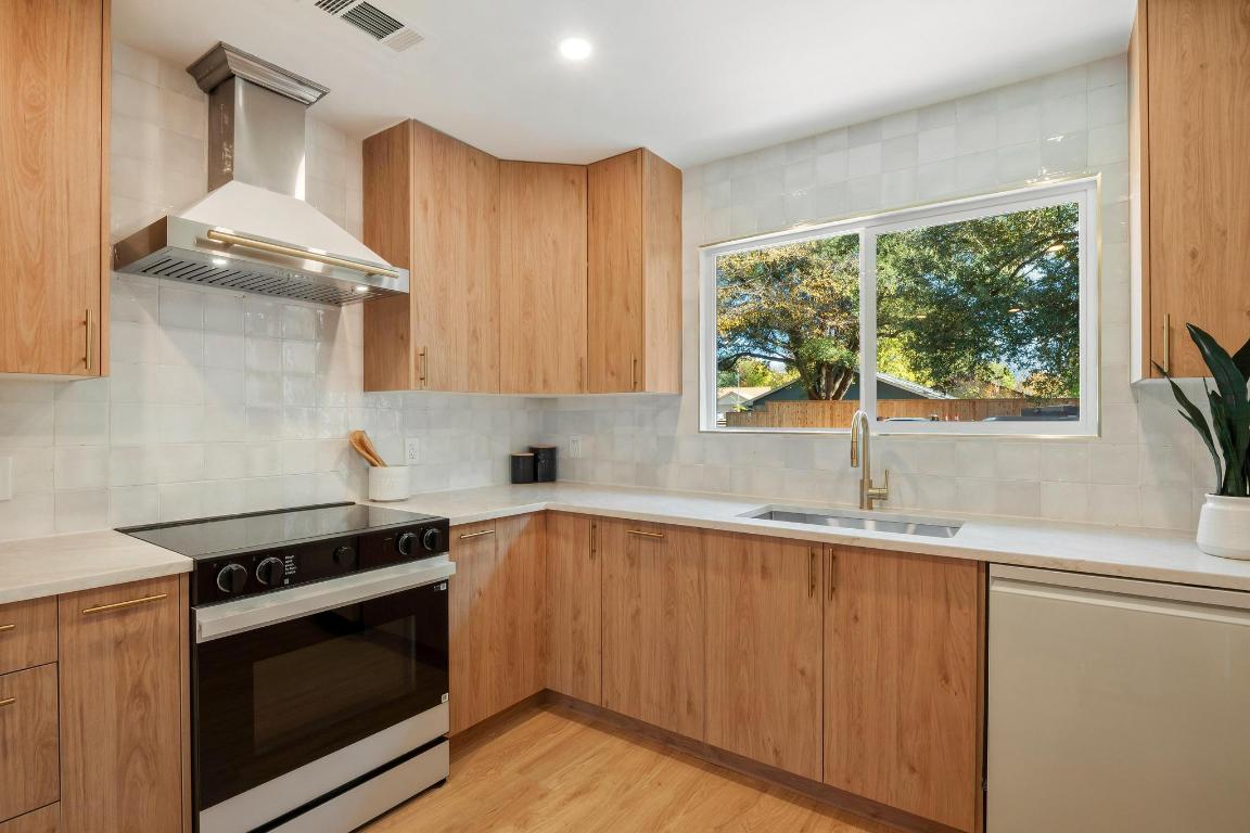 7010 Meadow Run Austin, TX 78745 - Photo 6 of 26 Kitchen featuring black electric range, modern cabinets, wall chimney exhaust hood, dishwashing machine, and decorative backsplash