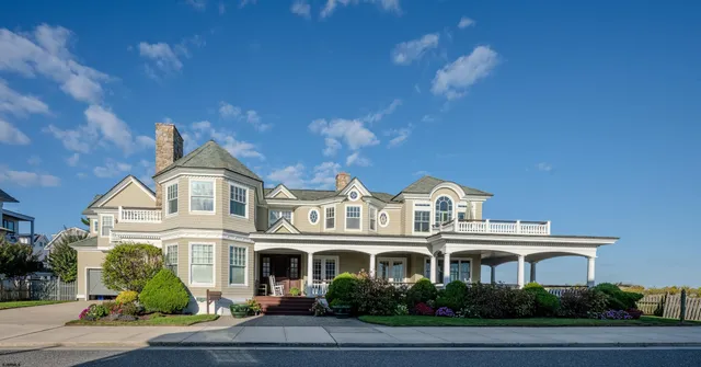 a front view of a house with swimming pool and trees in the background