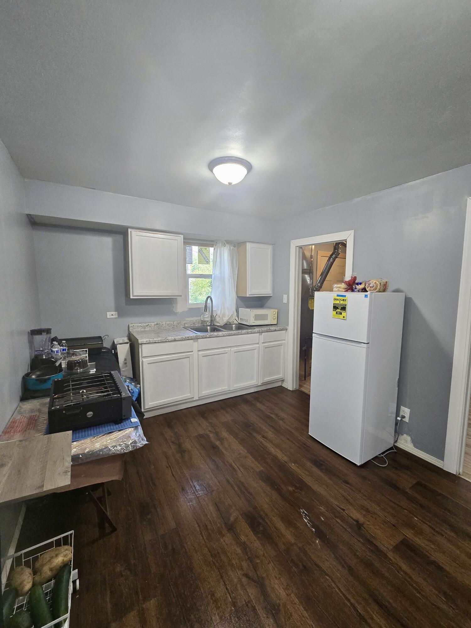 4613 Maryland Street Gary, IN 46409 - Photo 9 of 24 a kitchen with a refrigerator a stove a wooden floor and a table