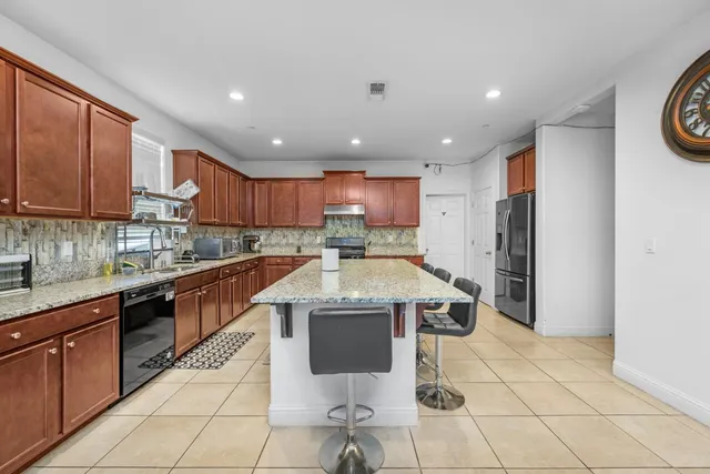 a open kitchen with stainless steel appliances granite countertop a refrigerator and a sink