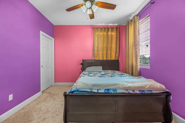 a bedroom with a bed a dresser and painting on the wall